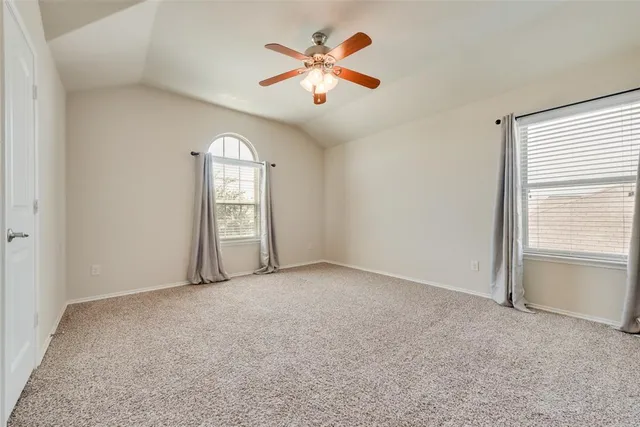 an empty room with chandelier fan and windows