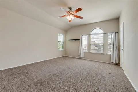 an empty room with windows and ceiling fan