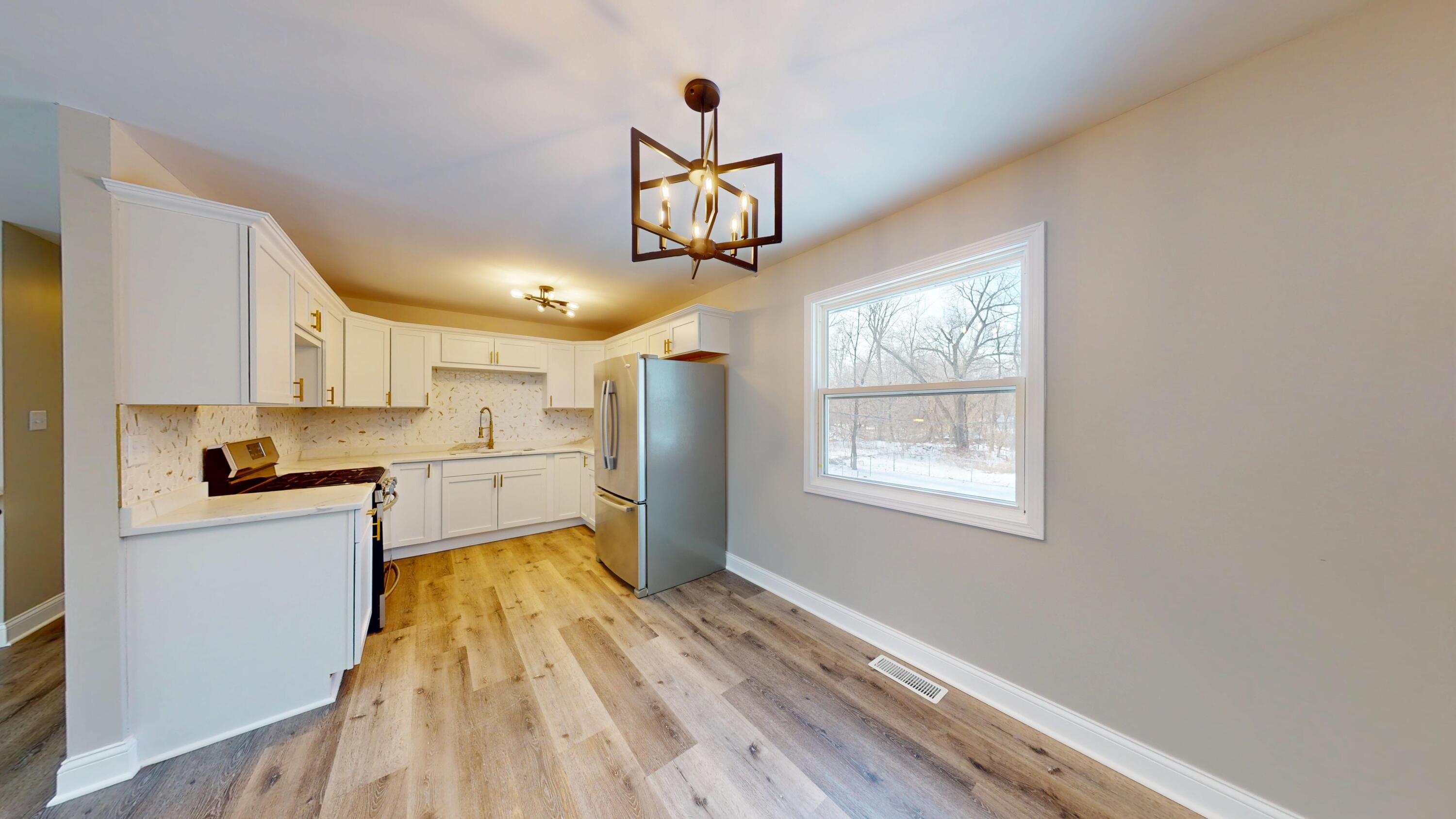 1528 Hanley Street Gary, IN 46406 - Photo 22 of 44 a kitchen with kitchen island granite countertop wooden floors and white cabinets