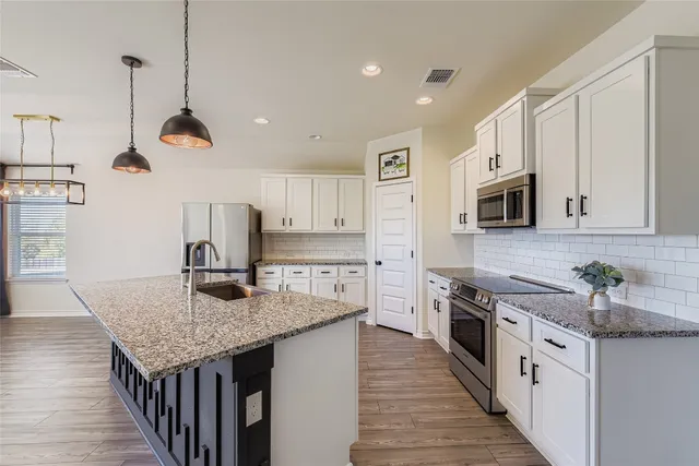 a kitchen with stainless steel appliances granite countertop a sink refrigerator and cabinets