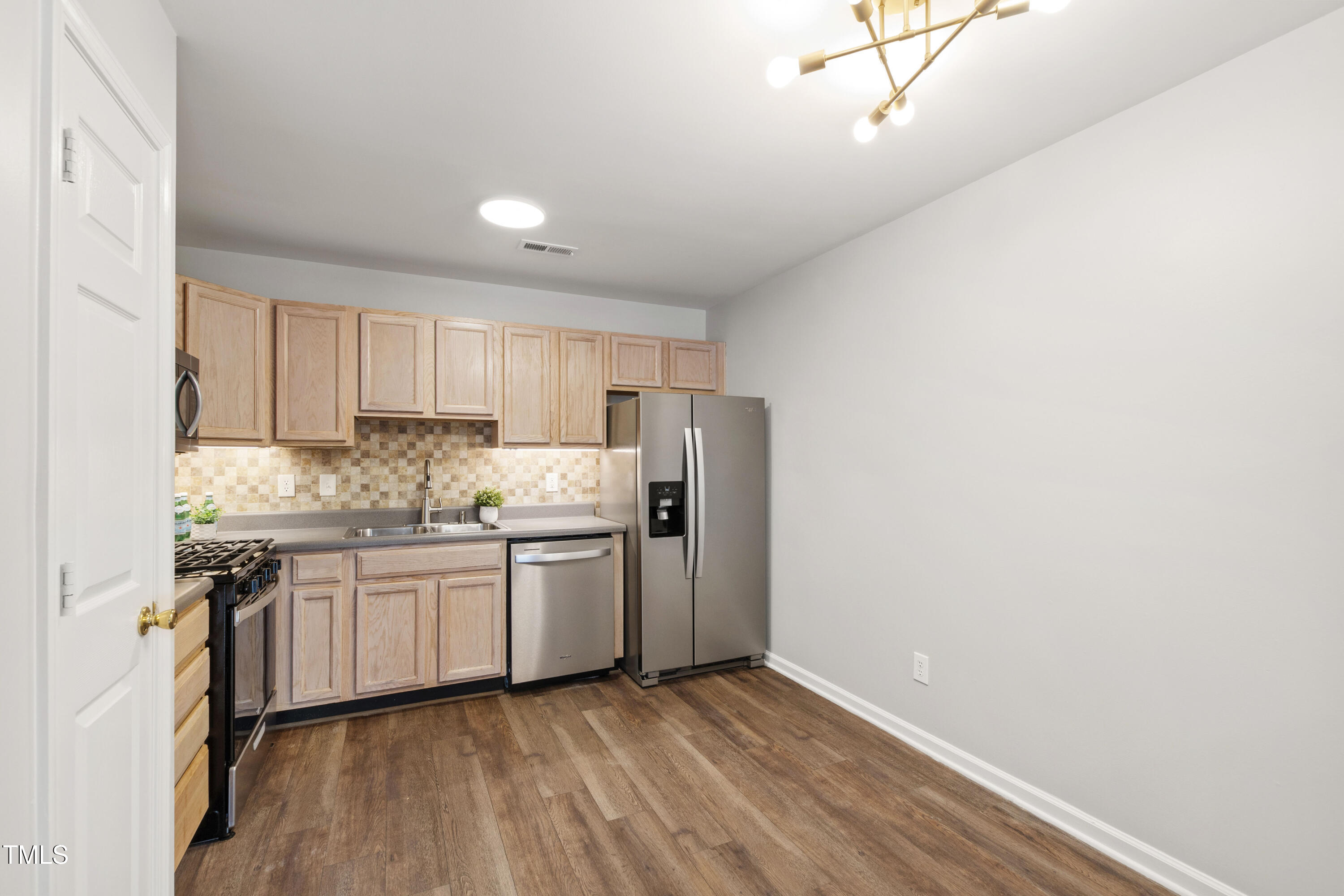 8610 Neuse Landing Lane, Unit 103 Raleigh, NC 27616 - Photo 15 of 28 a kitchen with stainless steel appliances granite countertop a stove a sink and a refrigerator