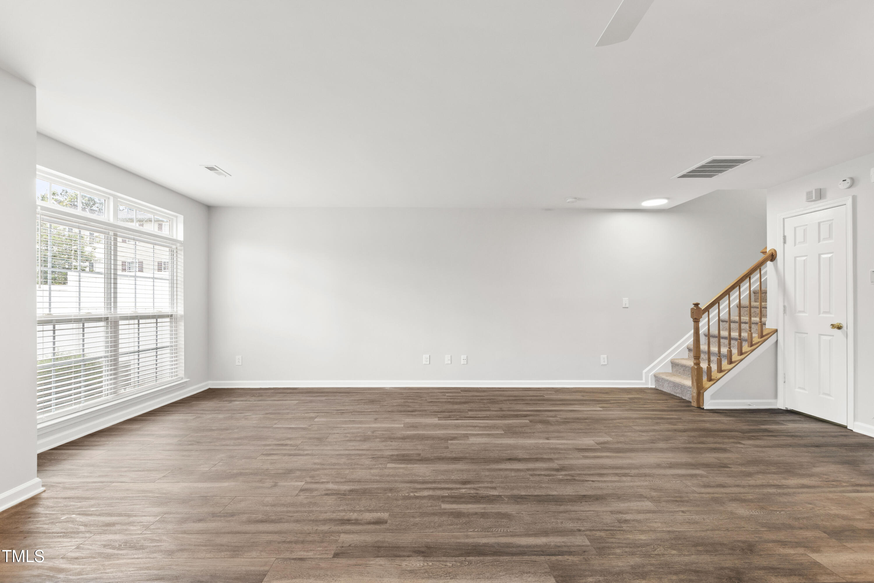8610 Neuse Landing Lane, Unit 103 Raleigh, NC 27616 - Photo 8 of 28 a view of an empty room with wooden floor and a window