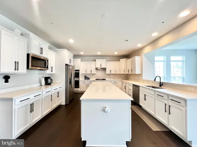 a large kitchen with stainless steel appliances lots of white cabinets and white appliances