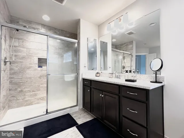 a bathroom with a double vanity sink mirror and shower