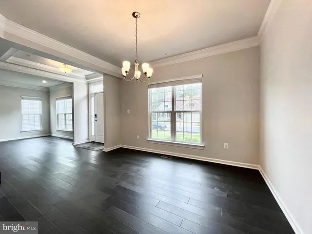 an empty room with wooden floor chandelier and windows