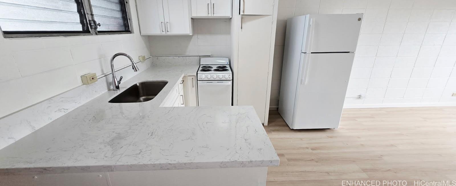 909 University Avenue, Unit 214 Honolulu, HI 96826 - Photo 4 of 13 a kitchen with stainless steel appliances a sink a stove and a refrigerator with wooden floor