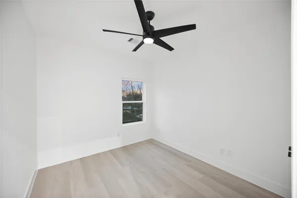 a view of a room with wooden floor and a ceiling fan