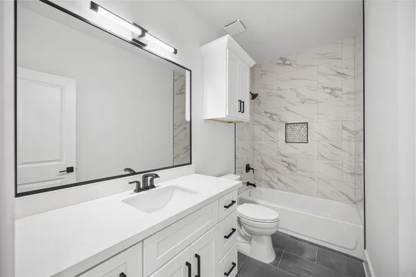 a bathroom with a granite countertop sink a toilet and shower