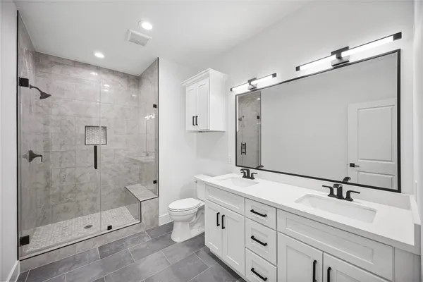 a bathroom with a double vanity sink mirror double shower and a toilet