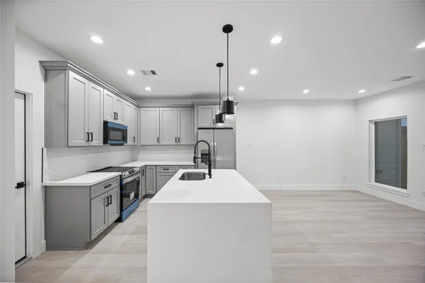 a kitchen with a sink a counter top space stainless steel appliances and cabinets