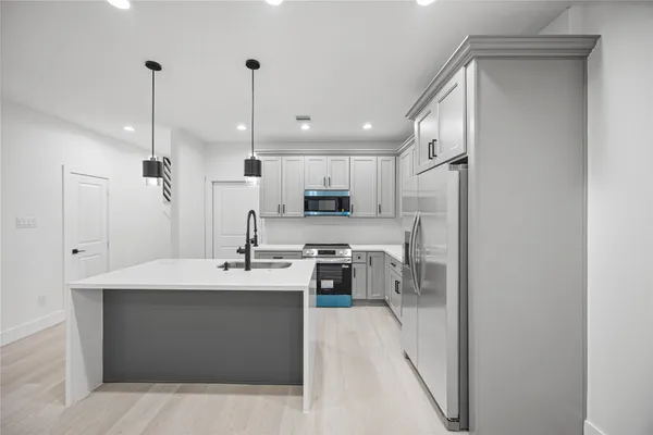 a kitchen with stainless steel appliances kitchen island granite countertop a sink and refrigerator