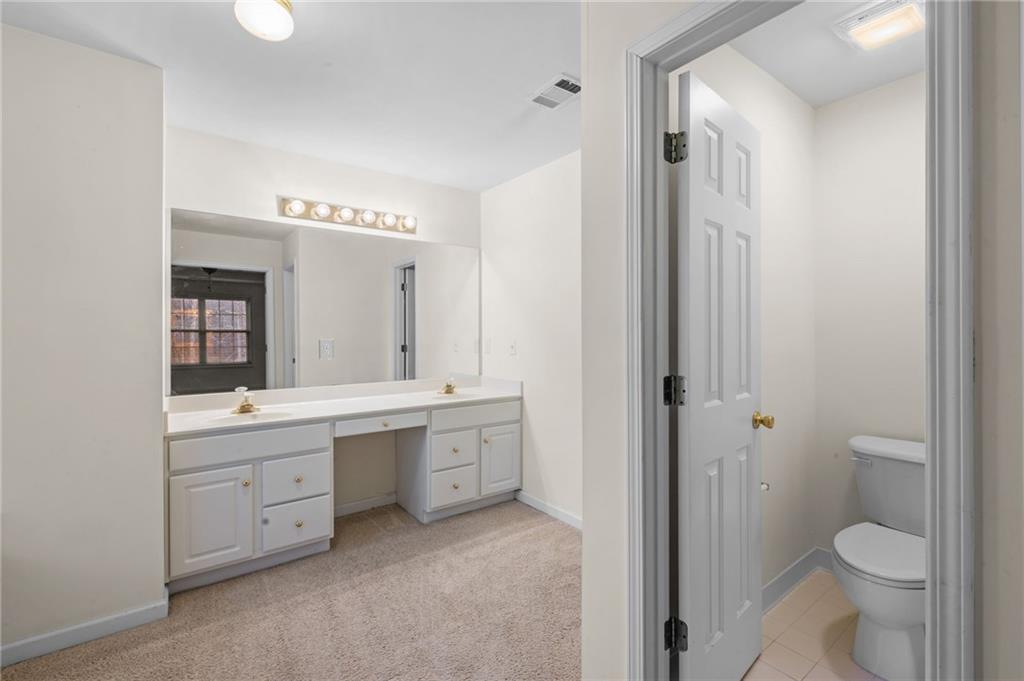 2935 Haynes Club Circle Southwest Grayson, GA 30017 - Photo 18 of 19 a spacious bathroom with a granite countertop toilet a sink and a mirror