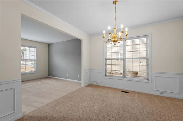an empty room with windows and chandelier fan