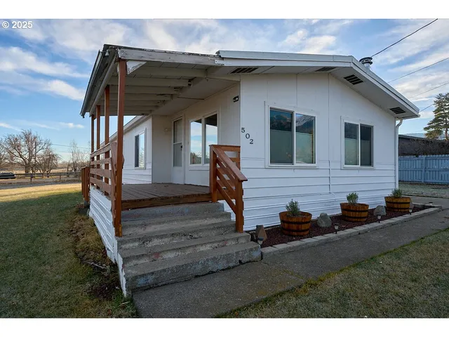 a view of house with wooden deck and furniture