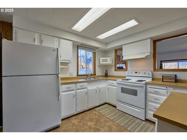 a kitchen with stainless steel appliances granite countertop a refrigerator a sink dishwasher a stove with white cabinets