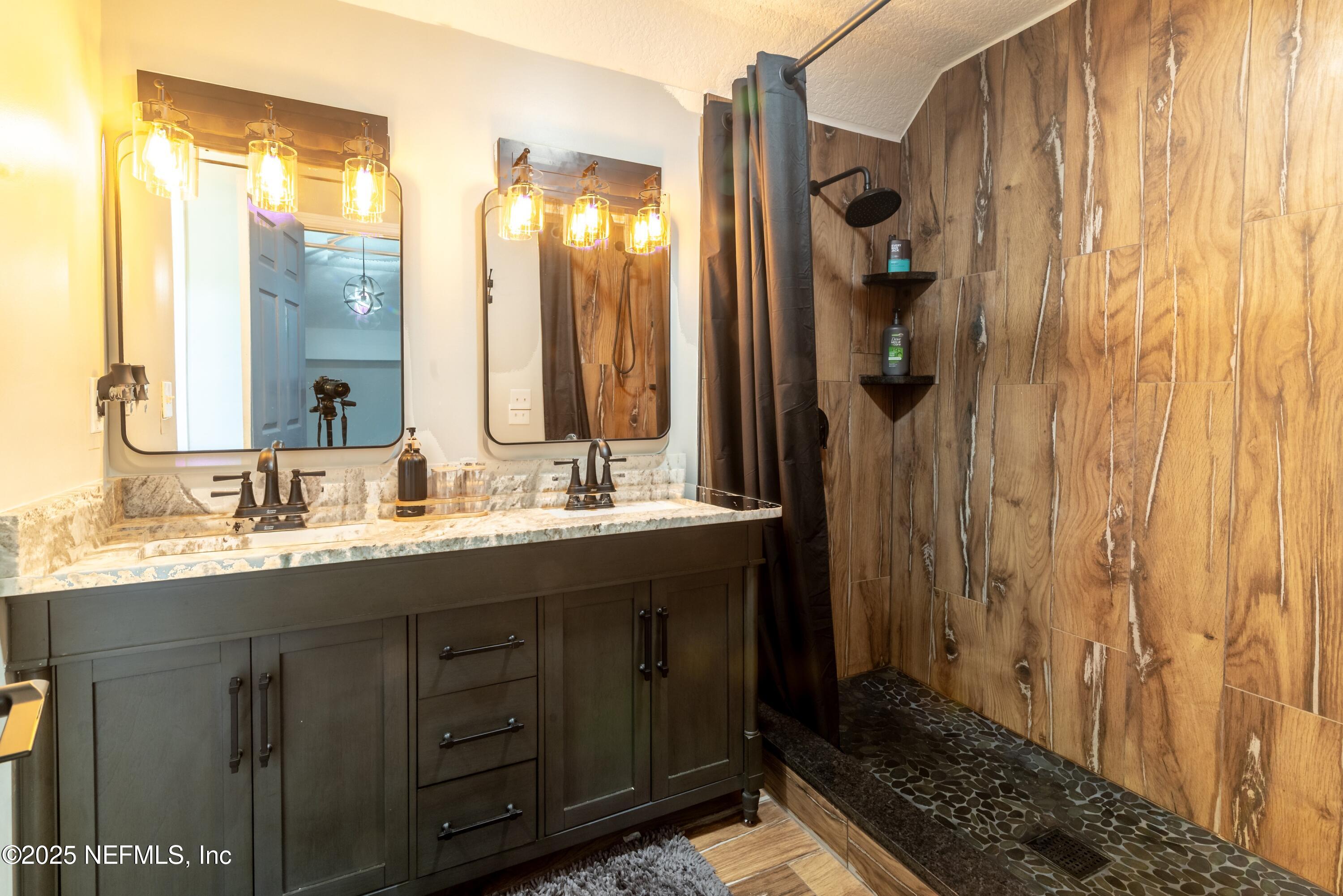 13561 Arnold Rhoden Road Glen St. Mary, FL 32040 - Photo 27 of 38 a bathroom with a double vanity sink a mirror a and a shower