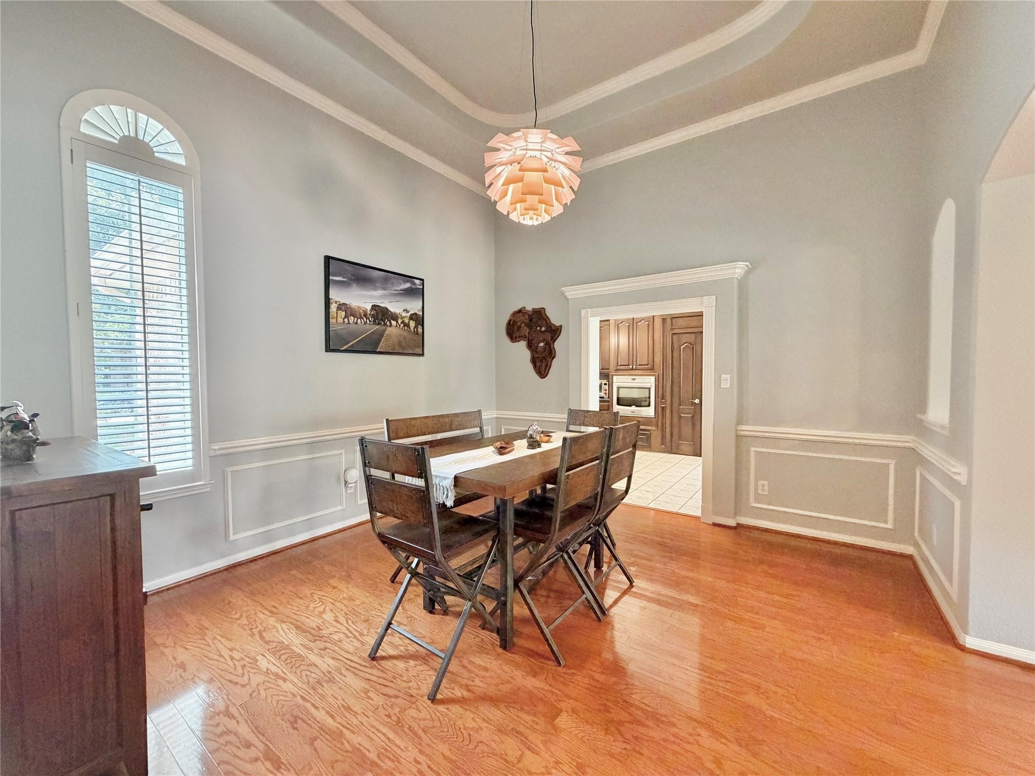 24818 Haverford Road Spring, TX 77389 - Photo 19 of 45 This dining area features elegant tray ceilings, warm wood flooring, and large windows with plantation shutter for natural light. The space is accented by a stylish light fixture.