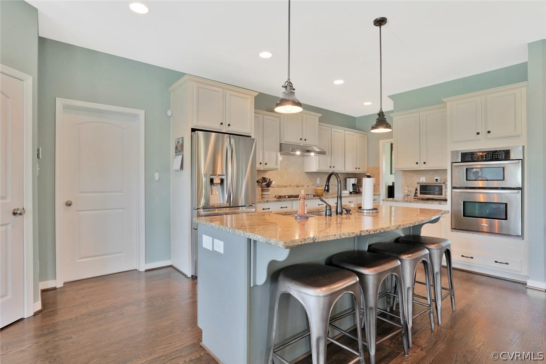 8910 Beaver Bridge Road Moseley, VA 23120 - Photo 11 of 44 a kitchen with stainless steel appliances kitchen island granite countertop a table chairs and a refrigerator