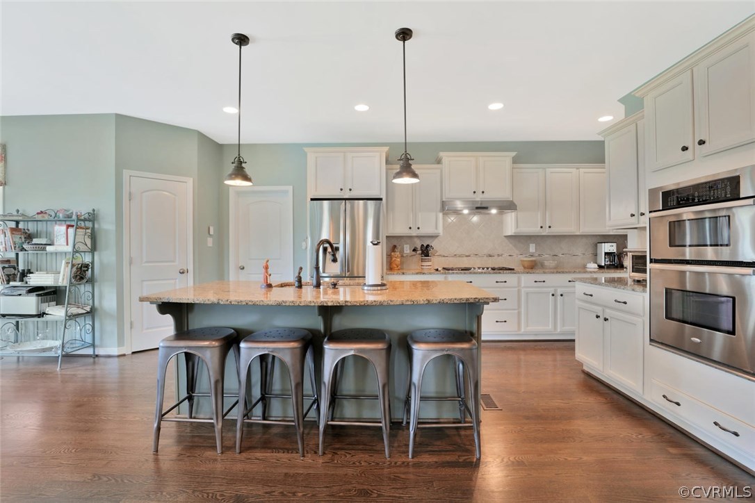 8910 Beaver Bridge Road Moseley, VA 23120 - Photo 10 of 44 a kitchen with stainless steel appliances granite countertop a sink a stove a refrigerator and island with wooden floor
