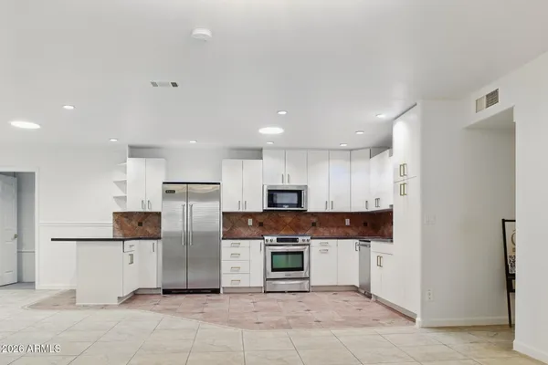 a kitchen with stainless steel appliances kitchen island granite countertop a refrigerator and a stove top oven