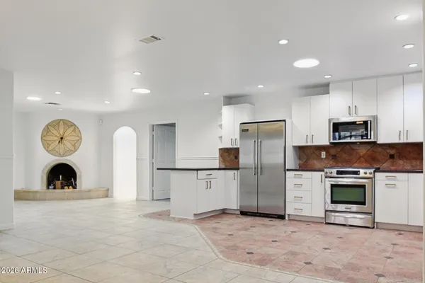 a large kitchen with stainless steel appliances granite countertop a refrigerator and a stove top oven