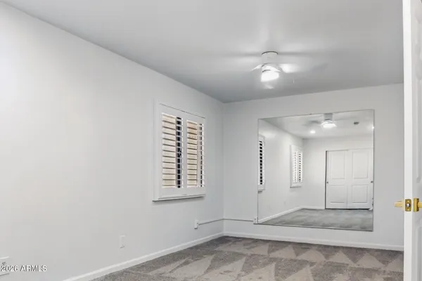 an empty room with windows and ceiling fan