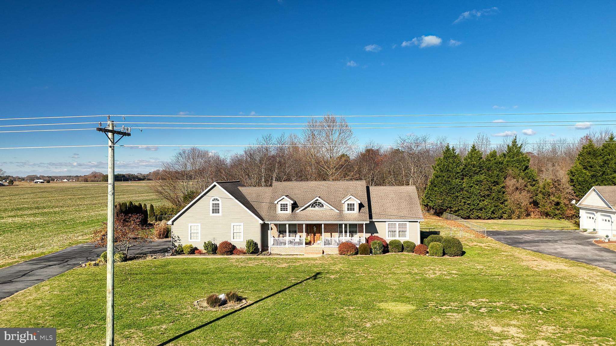 a view of a house next to a big yard with plants and large trees