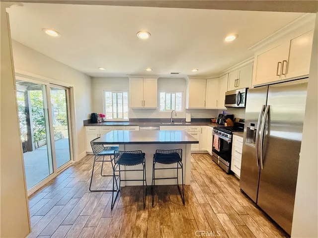 a kitchen with granite countertop a refrigerator a sink a stove a dining table and chairs