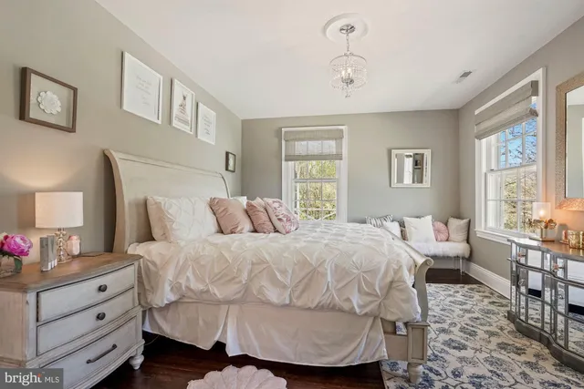 a bedroom with a bed a mirror on dresser and a window