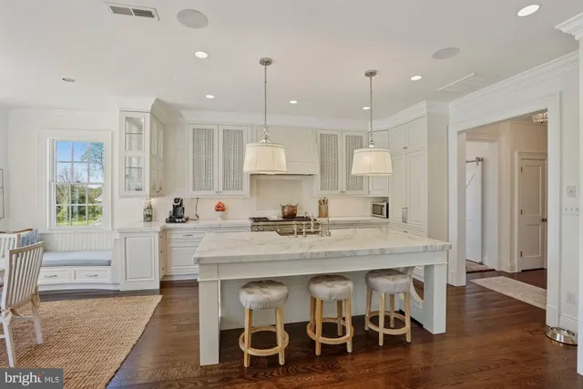 a kitchen with stainless steel appliances granite countertop a table chairs sink and cabinets
