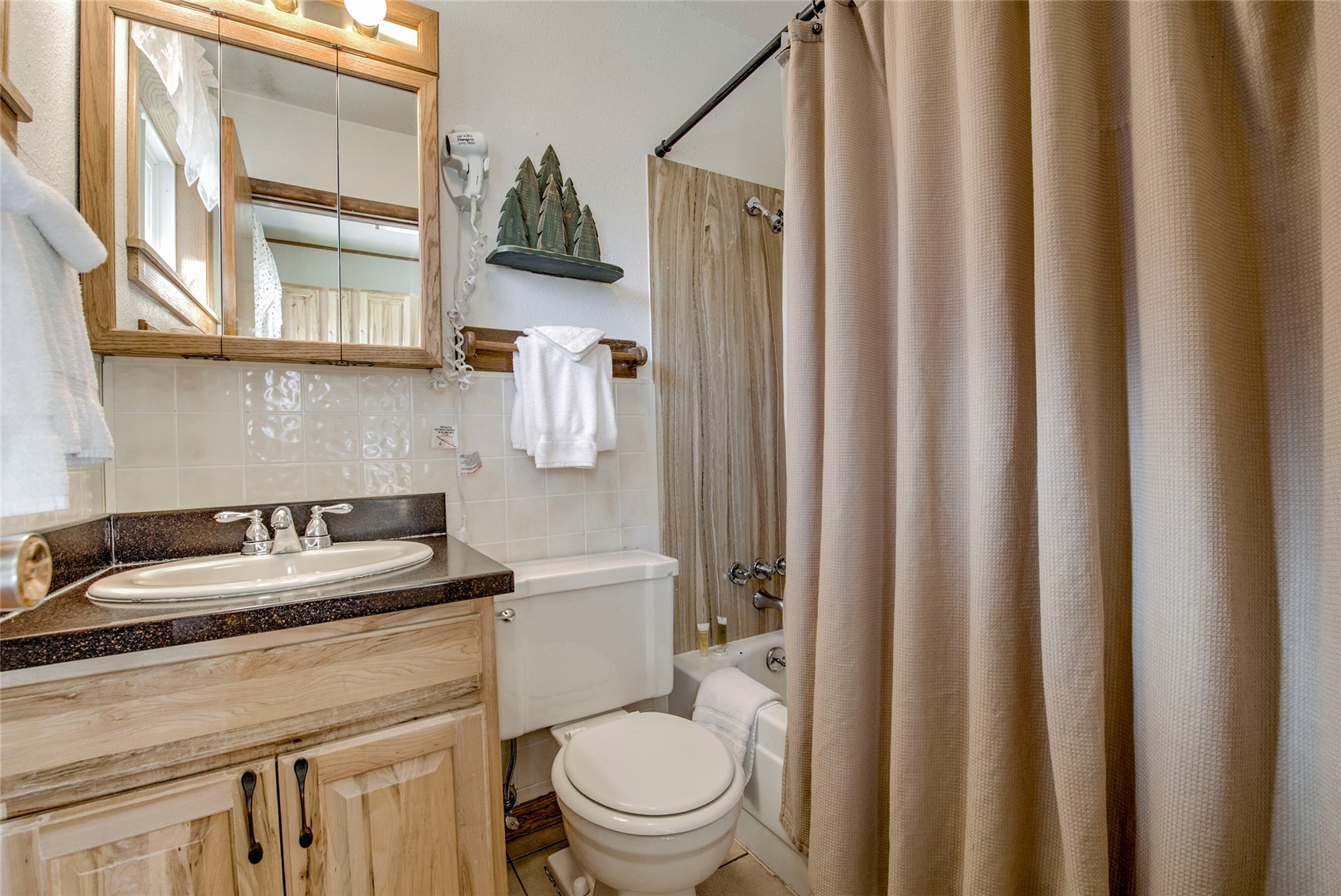 Full bathroom featuring decorative backsplash, toilet, tile walls, vanity, and shower / bathtub combination with curtain