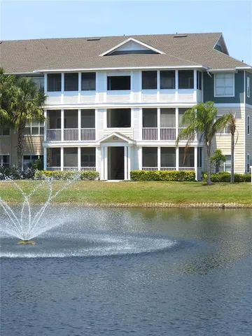 a view of a brick house with a yard and large trees