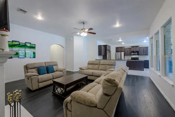 a living room with furniture kitchen view and a chandelier