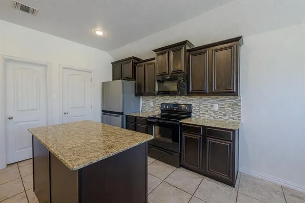 a kitchen with stainless steel appliances granite countertop a stove refrigerator and microwave