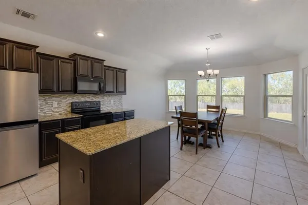 a kitchen with kitchen island granite countertop a sink counter and chairs