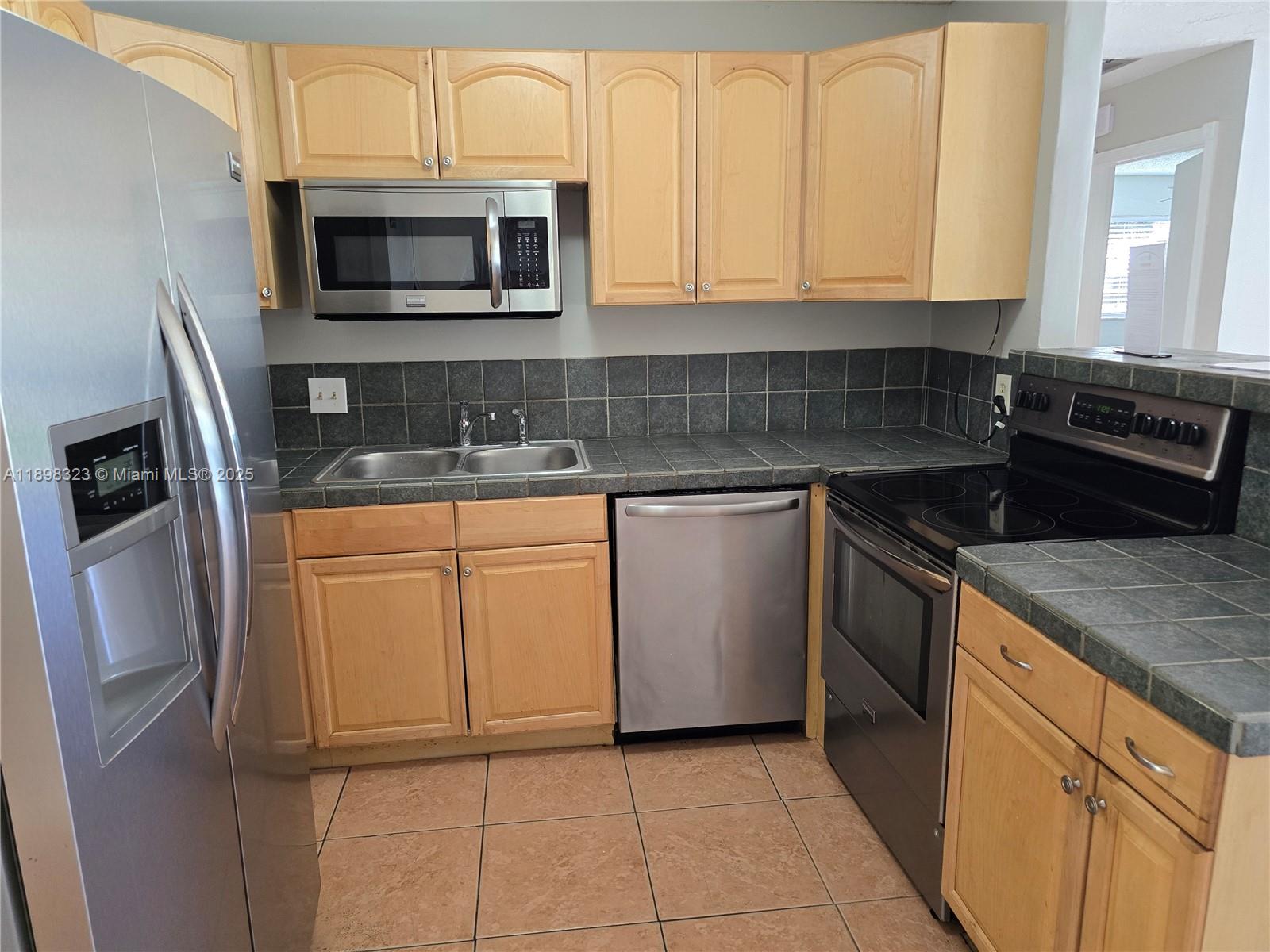 1260 Southeast St Lawrence Way Stuart, FL 34997 - Photo 4 of 14 a kitchen with granite countertop a sink stove and microwave