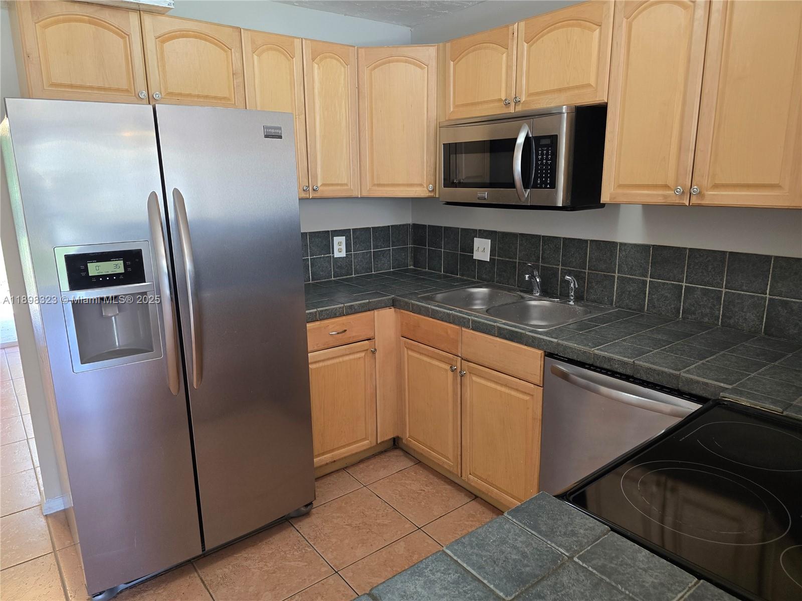 1260 Southeast St Lawrence Way Stuart, FL 34997 - Photo 5 of 14 a kitchen with stainless steel appliances granite countertop a refrigerator a microwave a sink and dishwasher