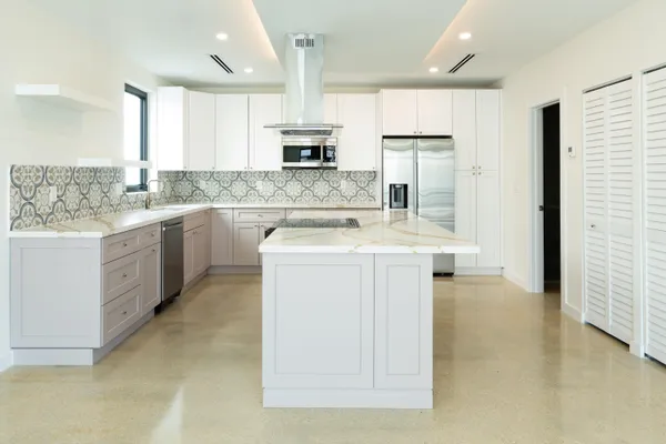 a kitchen with stainless steel appliances granite countertop a stove top oven a sink and white cabinets