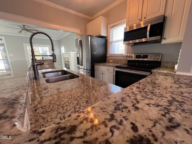 a kitchen with stainless steel appliances kitchen island granite countertop a stove refrigerator and sink