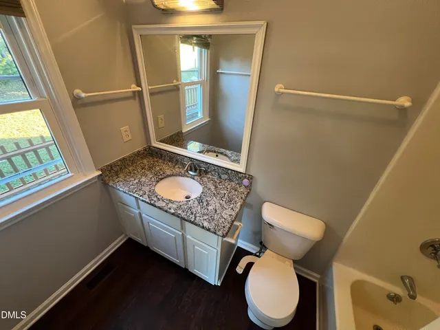 a bathroom with a granite countertop toilet sink and mirror