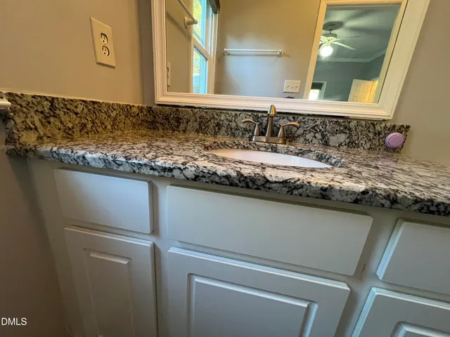 a bathroom with a granite countertop sink and a mirror