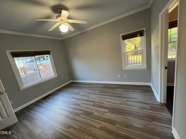 an empty room with wooden floor chandelier fan and windows