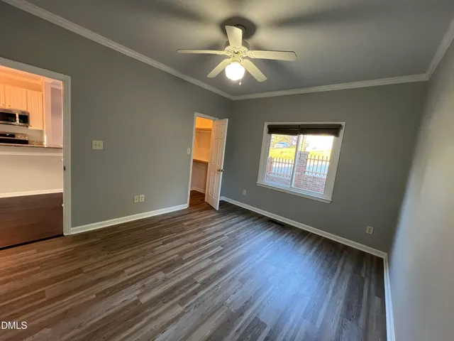 an empty room with wooden floor fan and windows