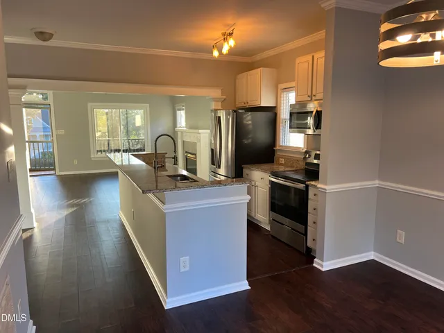 a kitchen with stainless steel appliances a stove a refrigerator a sink a stove and wooden floor