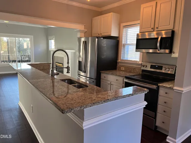 a kitchen with stainless steel appliances granite countertop a sink a stove and a refrigerator