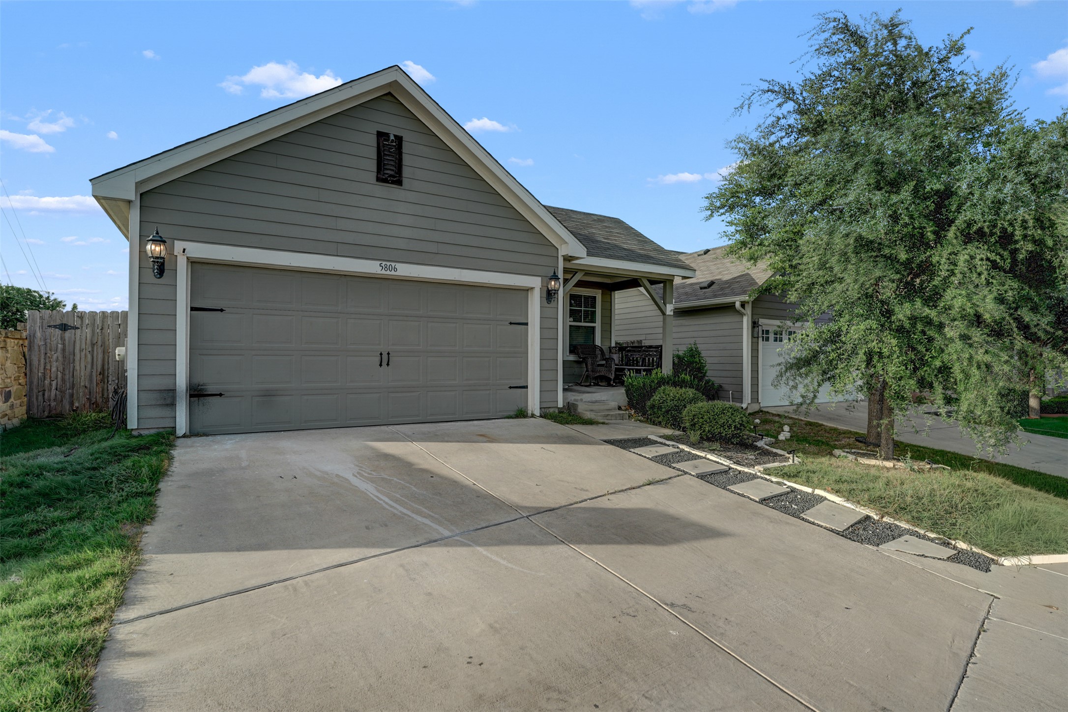 5806 Aviano Road Round Rock, TX 78665 - Photo 4 of 29 An inviting front elevation features a welcoming porch, a practical attached garage, and a lush tree for natural shade.