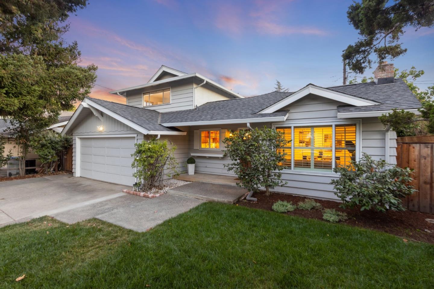 a backyard of a house with table and chairs plants and large tree
