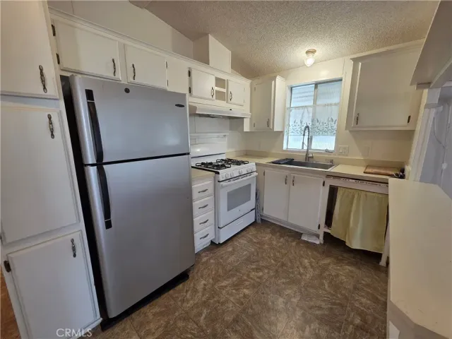 a kitchen with stainless steel appliances a refrigerator a sink a stove a microwave and cabinetry