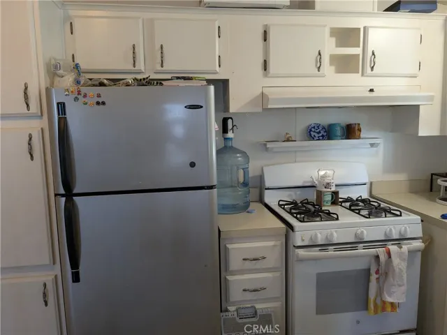 a kitchen with stainless steel appliances granite countertop a refrigerator sink stove and cabinets