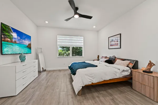 a bedroom with a bed and a flat tv screen on dresser